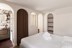 Ein Hotelzimmer mit einem großen Bett, einem Badezimmer mit Marmorwaschtisch und Blick auf den Flur.