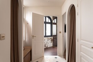 Ein Flur mit einer Bank, einer zur Zimmer mit Fenster führenden Tür und einem an der Wand befestigten Lichtschalter.