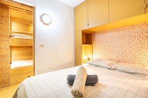 Une chambre à coucher avec un lit, une armoire et un luminaire rond fixé au mur.