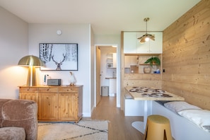 Un salon moderne avec un meuble en bois, une lampe, un tableau encadré, un canapé, une table basse et un luminaire suspendu.