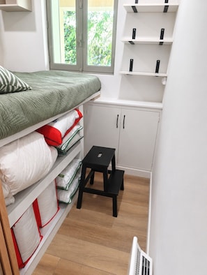 A bedroom with a bed, storage cabinets, a small stool, and a window with a view of greenery. - Les Envols de Chamrousse - Proche Télécabines (Chamrousse)