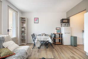 A compact living space with a dining table, chairs, a sofa, a kitchen area with a microwave, and a refrigerator. - Les Envols de Chamrousse - Proche Télécabines (Chamrousse)