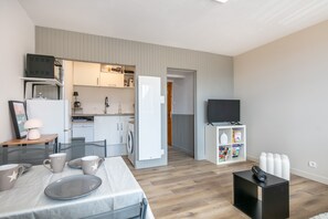 Ein kompakter Wohnbereich mit Küchenzeile, Essbereich und Fernseher.