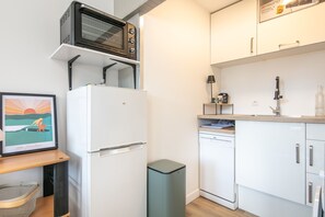 Eine kleine Küche mit einem weißen Kühlschrank, einer Mikrowelle und einem Geschirrspüler.