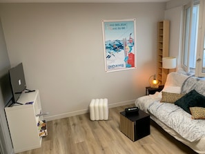 A modern living room with a flat-screen TV, a sofa, a lamp, and a poster on the wall. - Les Envols de Chamrousse - Proche Télécabines (Chamrousse)