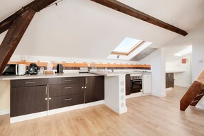 A modern kitchen with dark cabinetry, a white countertop, and a skylight. - Le Vivaldi - Proche de la Gare (Nancy)