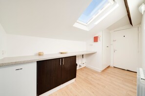 A modern kitchen with a skylight, dark cabinets, and a light countertop. - Le Vivaldi - Proche de la Gare (Nancy)