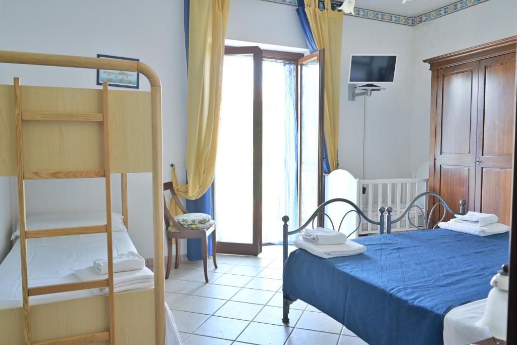 Une chambre avec un lit superposé, un lit simple, une chaise, un téléviseur et une armoire.