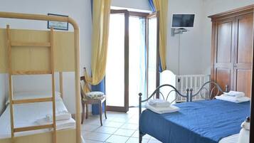 Une chambre avec un lit superposé, un lit simple, une chaise, un téléviseur et une armoire.