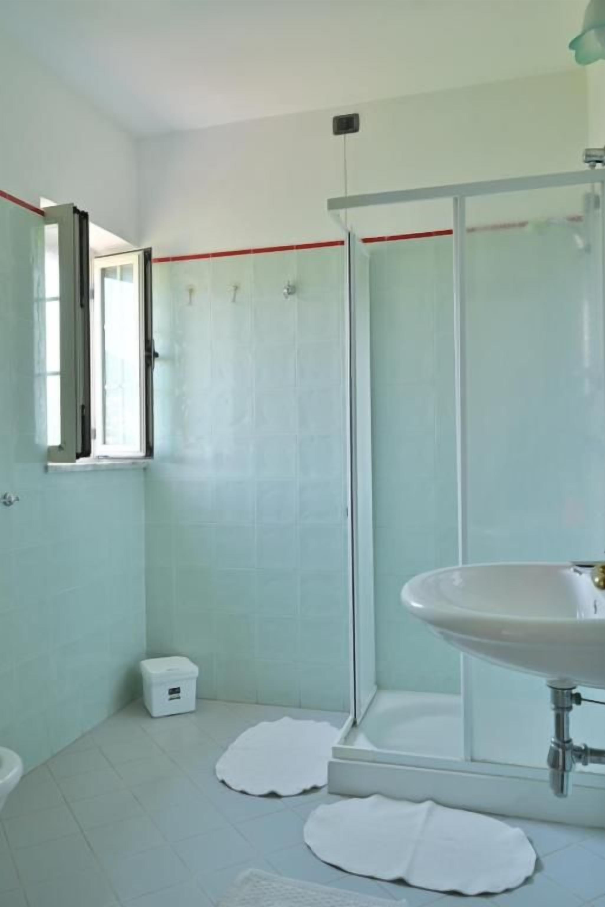 Un bagno con doccia, lavandino e servizi igienici.