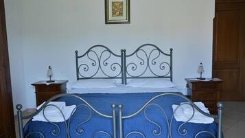 A bed with a metal frame, a blue bedspread, and white linens. There are two bedside tables with lamps.