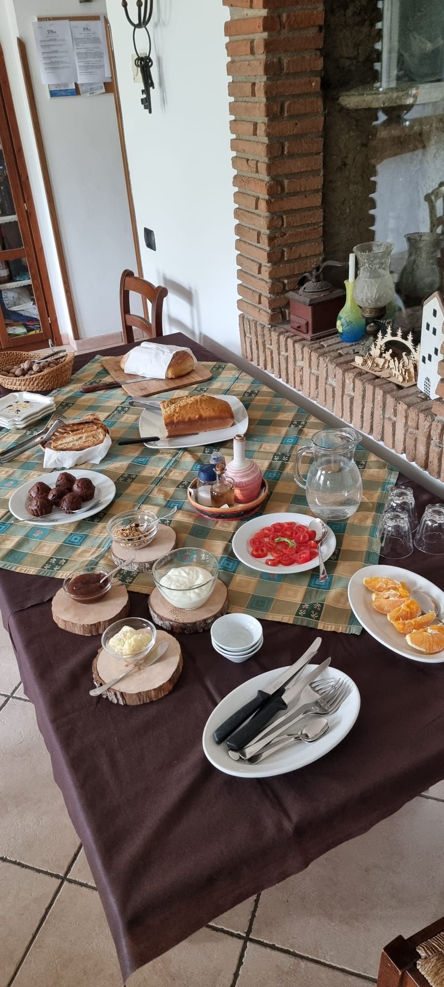 Une table à manger dressée avec différents plats, couverts et une cheminée en briques.