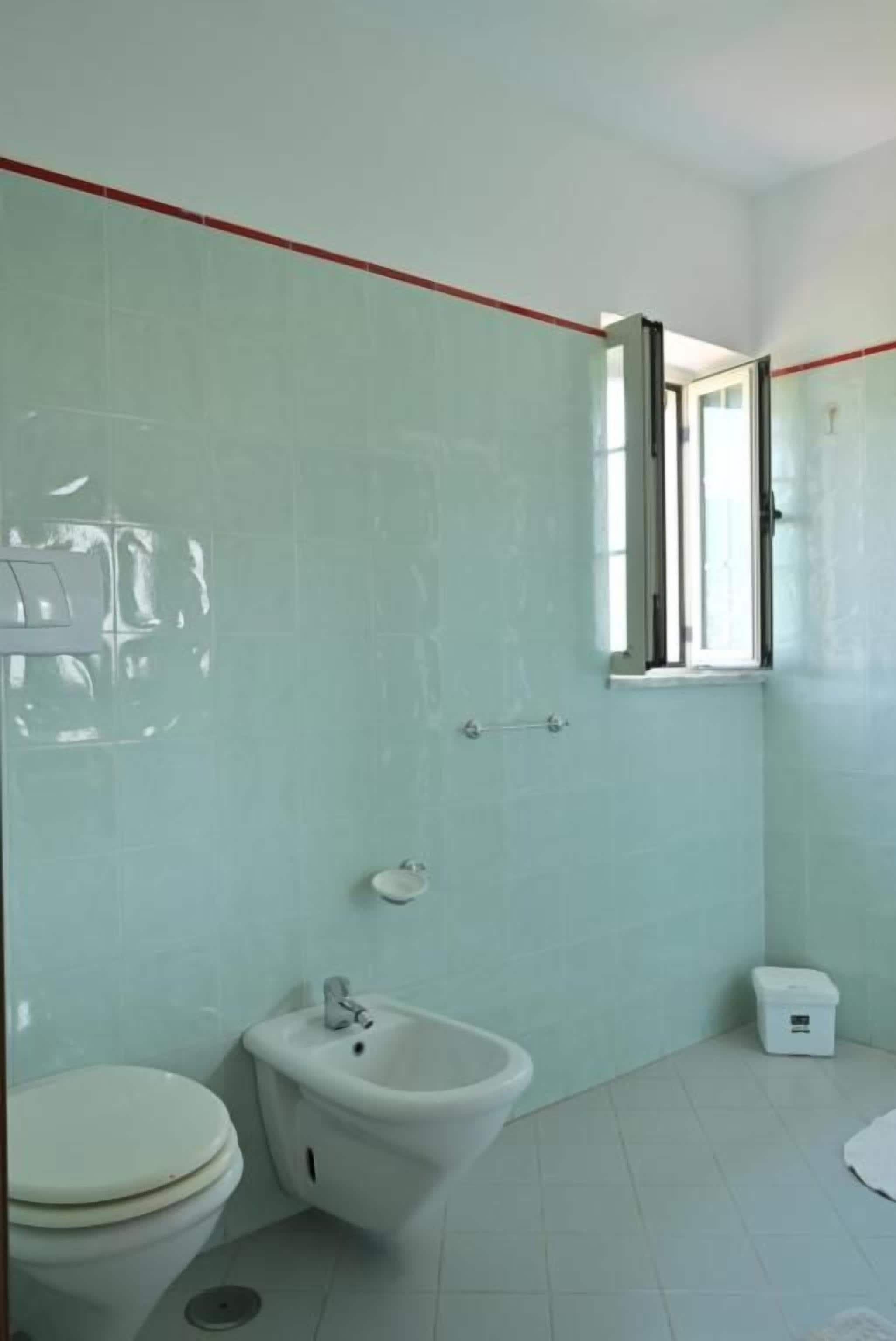 Une salle de bain avec des toilettes, un bidet et une petite fenêtre.