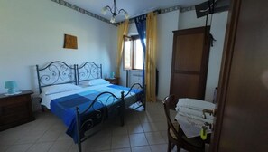 Une chambre à coucher comprenant un lit, une table de chevet, une chaise, une armoire et une fenêtre avec des rideaux.