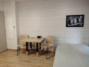 A small room with a wooden floor, a bed, a table with two chairs, and a wall-mounted picture. - Studio with a swimming pool and views of the countryside (Ax-les-Thermes)