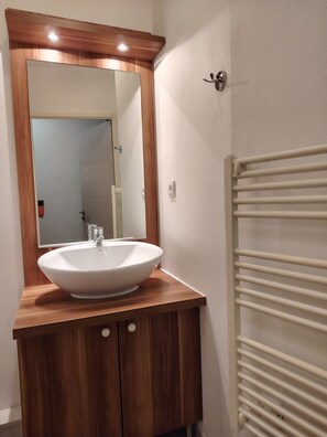 A bathroom with a wooden vanity, a white sink, and a mirror. - Studio with a swimming pool and views of the countryside (Ax-les-Thermes)