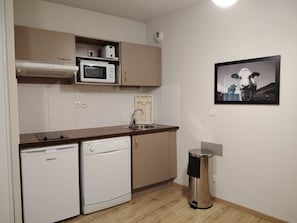 A compact kitchen with a microwave, a sink, a dishwasher, and a trash bin. - Studio with a swimming pool and views of the countryside (Ax-les-Thermes)