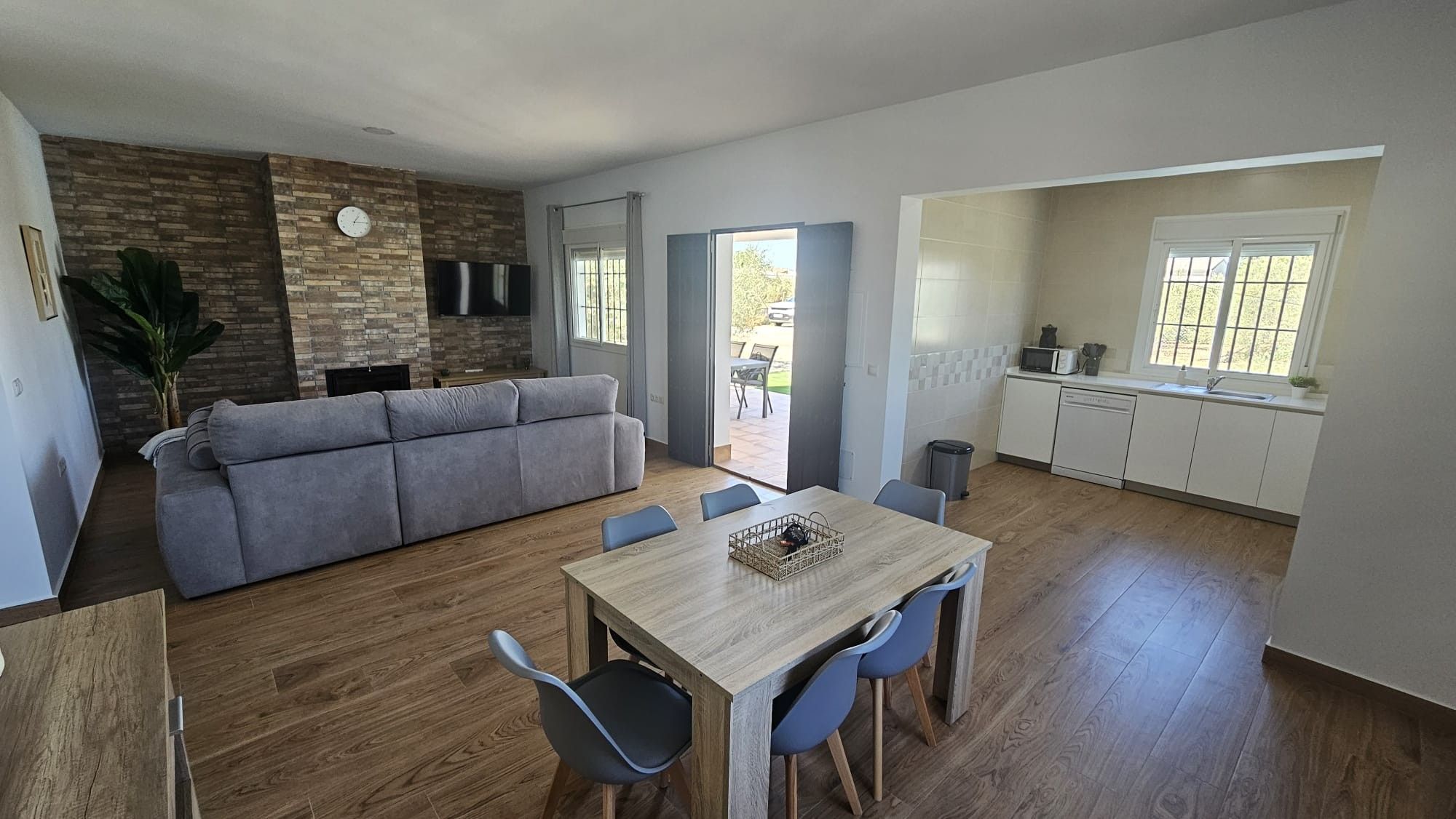 A modern living space with a sofa, dining table, and kitchen area.