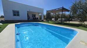 A rectangular swimming pool with a clear blue water surface, surrounded by a concrete deck.