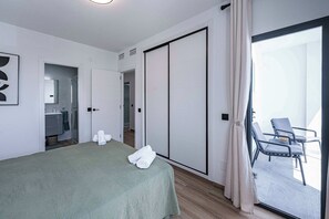 Ein Hotelzimmer mit Bett, Bad, Schiebetürenschrank und Balkon mit Stuhl.