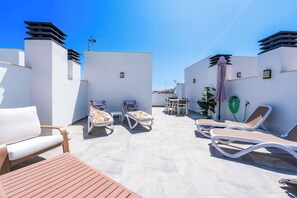 Eine Dachterrasse mit Liegestühlen, einem Tisch und einem Blumentopf.