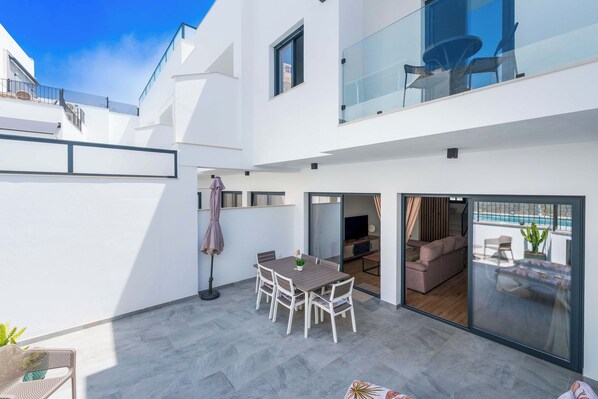 Un appartement moderne doté d’un patio, d’un coin repas et d’un salon avec vue sur la piscine.