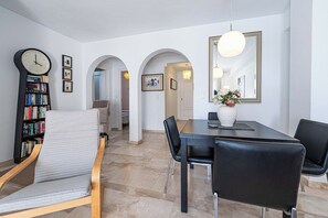 Un comedor con una mesa, sillas, un reloj y una estantería.