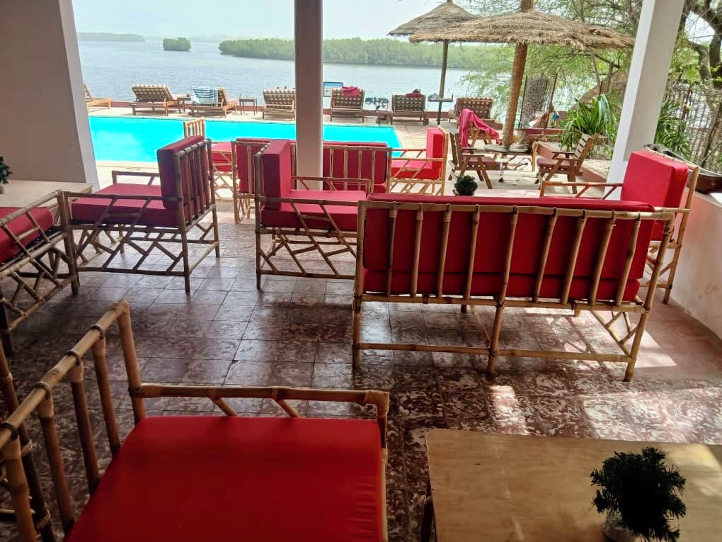 Zona junto a la piscina con mobiliario de mimbre y vista al mar.