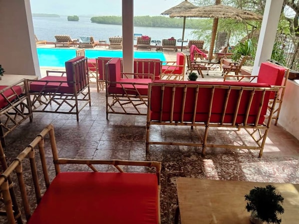 A poolside area with wicker furniture and a view of the sea.