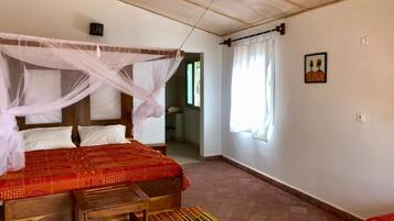 Un dormitorio con cama, mesita de noche, ventana con cortinas e imagen colgada en la pared.