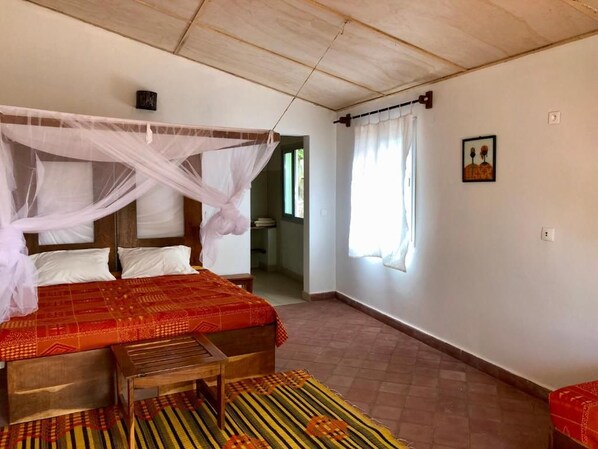 Un dormitori amb un llit, una taula de nit, una finestra amb cortines i un quadre penjat a la paret.