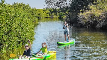 Un río tranquilo con dos kayaks y una persona practicando paddleboard.