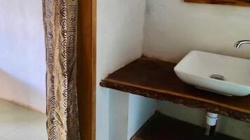 Een compacte badkamer met een enkele wastafel, een spiegel en een decoratief gordijn.