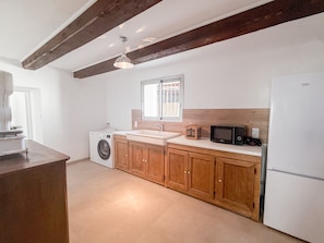 Eine Küche mit Holzausstattung, einer Waschmaschine, einem Spülbecken, einer Mikrowelle und einem Kühlschrank.