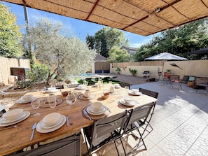 An outdoor dining area with a table set for a meal, surrounded by chairs and an umbrella. - Le Mas de Menard (Barbentane)