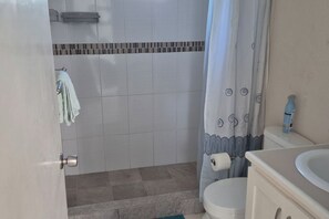 Un baño con ducha, inodoro y lavabo.