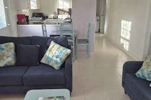 A living room with a sofa, a coffee table, and a dining area with a table and chairs.