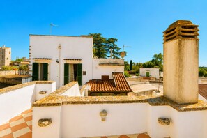 A rooftop terrace with a tiled floor, a chimney, and a white building with green shutters. - GuestHost - Lioy Suite with Terrace (Sovereto)