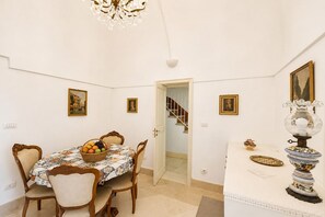 A dining room with a table set for four, a chandelier, and a staircase leading to another level. - GuestHost - Lioy Suite with Terrace (Sovereto)