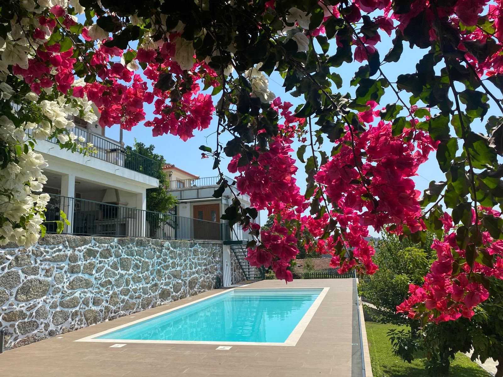 Une piscine avec un mur en pierre et un balcon doté d’une balustrade.