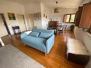 A living room with a sofa, a dining table with chairs, and a window. - Casa do Laranjal (Curvos)