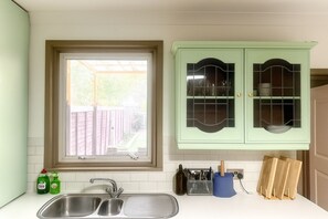A kitchen with a window, a sink, and green cabinets.