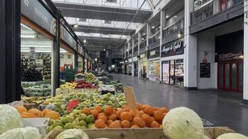 An indoor market with various stalls selling fruits and vegetables.