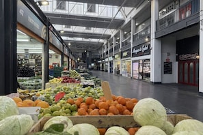 Un mercado cubierto con varios puestos que venden frutas y verduras.