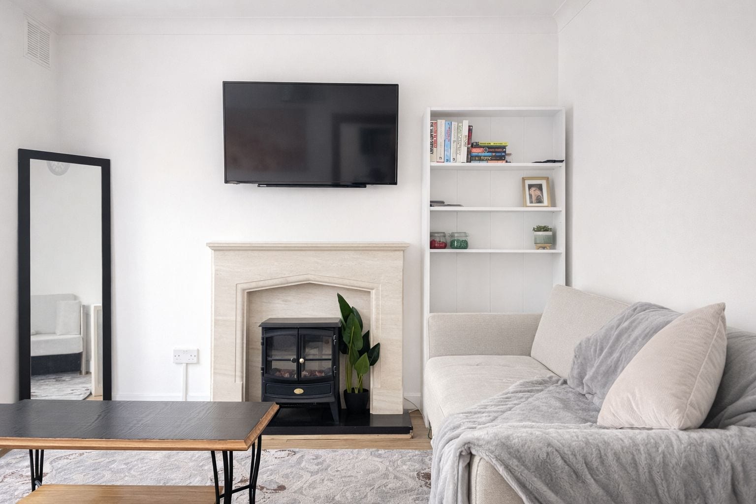 A living room with a fireplace, a television mounted on the wall, a bookshelf, and a sofa.
