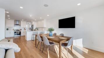 Een moderne keuken met witte kasten, een centraal eiland en een eethoek met een houten tafel en stoelen.