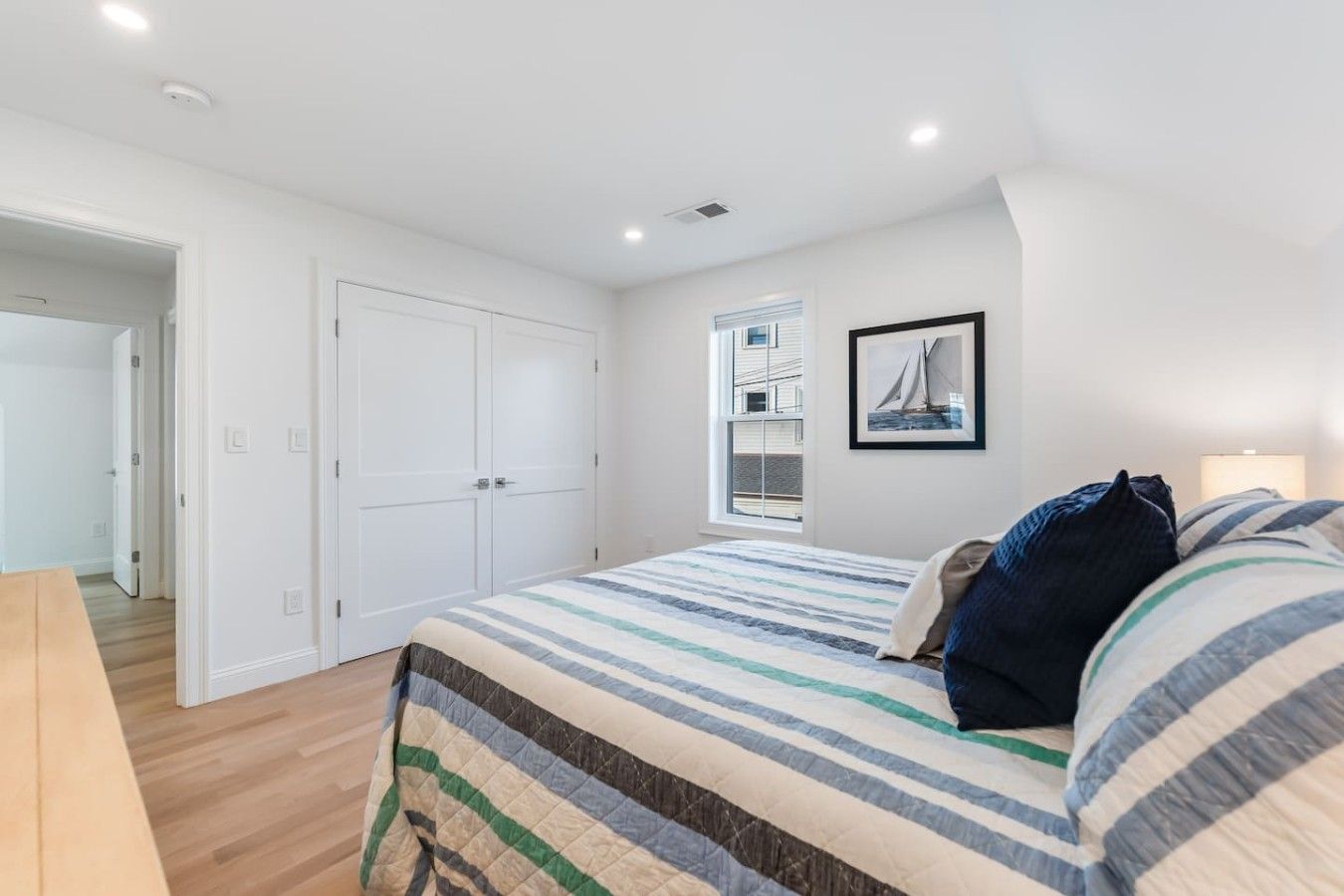 A bedroom with a bed, a window with a view, a door, and a light fixture.