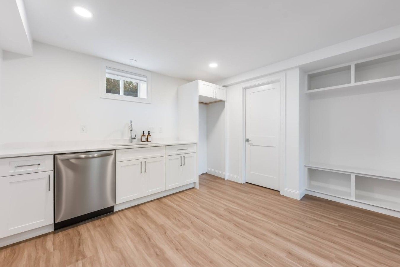 Une cuisine moderne avec des meubles blancs, un lave-vaisselle en acier inoxydable et une fenêtre au-dessus de l’évier.