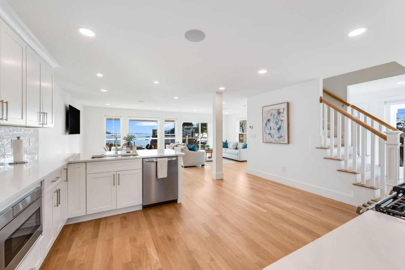 A modern kitchen with white cabinetry, a central island, and a view to the outside.