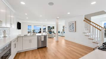 A modern kitchen with white cabinetry, a central island, and a view to the outside.